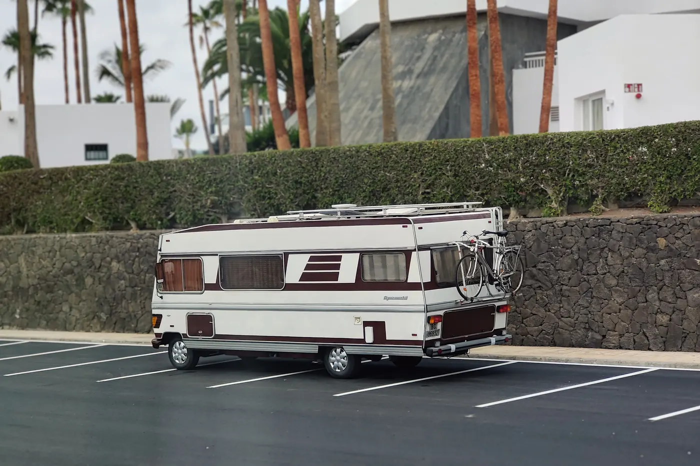 Vintage motorhome parked in a public car park lined with palm trees in Lanzarote