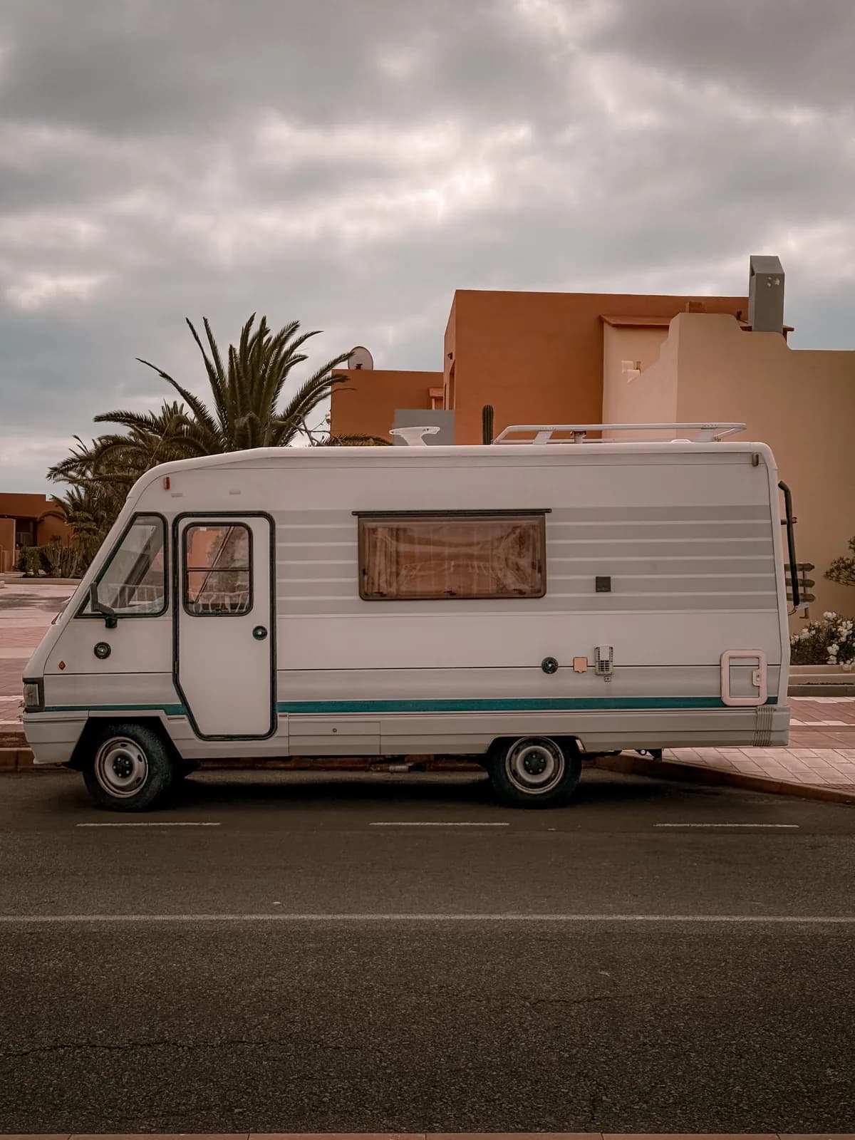 Alter Campervan in einer Dorfstraße auf Fuerteventura, vor kanarischen Häusern und einer Palme