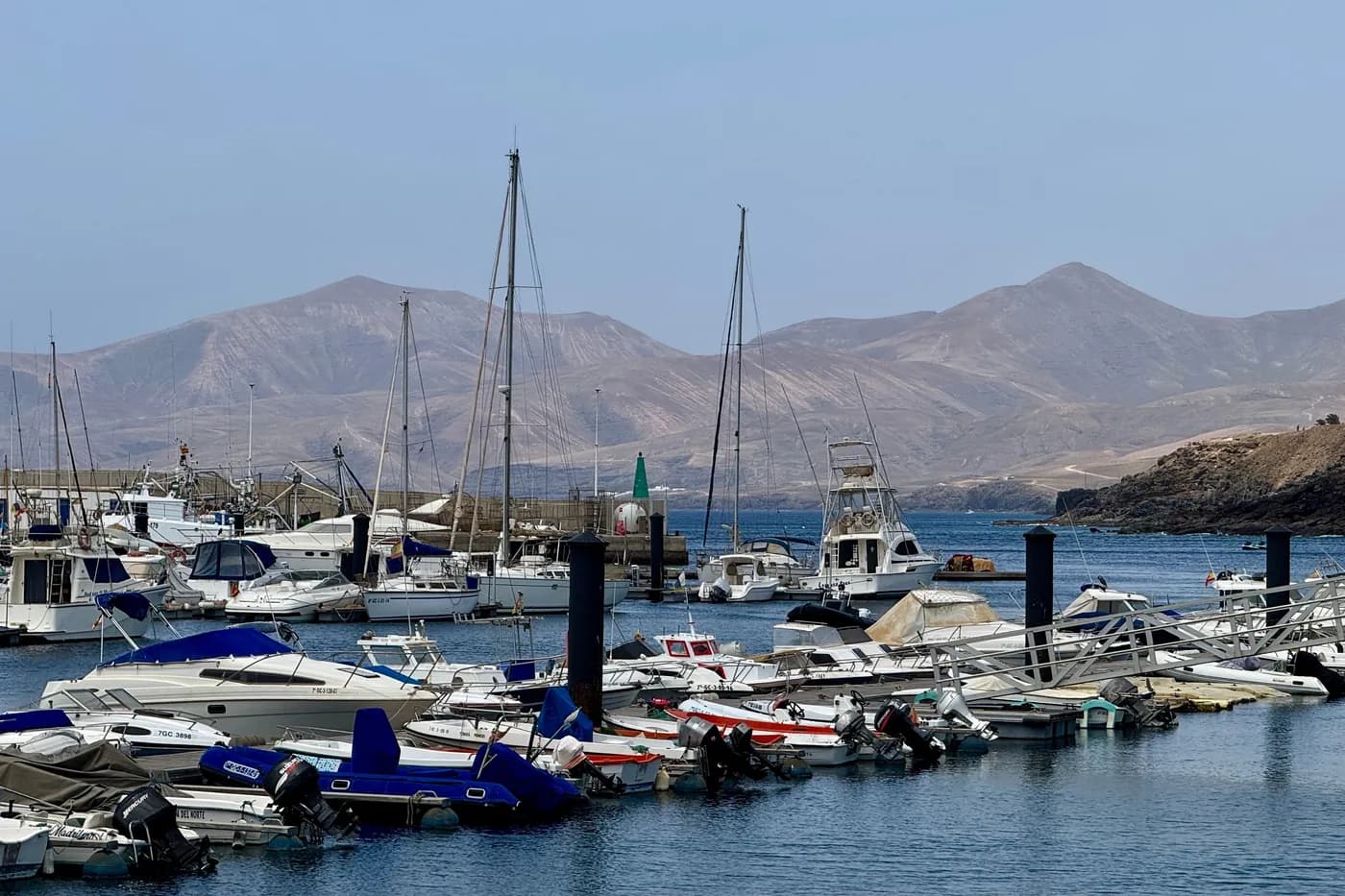 Segel- und Motorboote in einer Marina von Playa Blanca, im Hintergrund die Berge von Fuerteventura