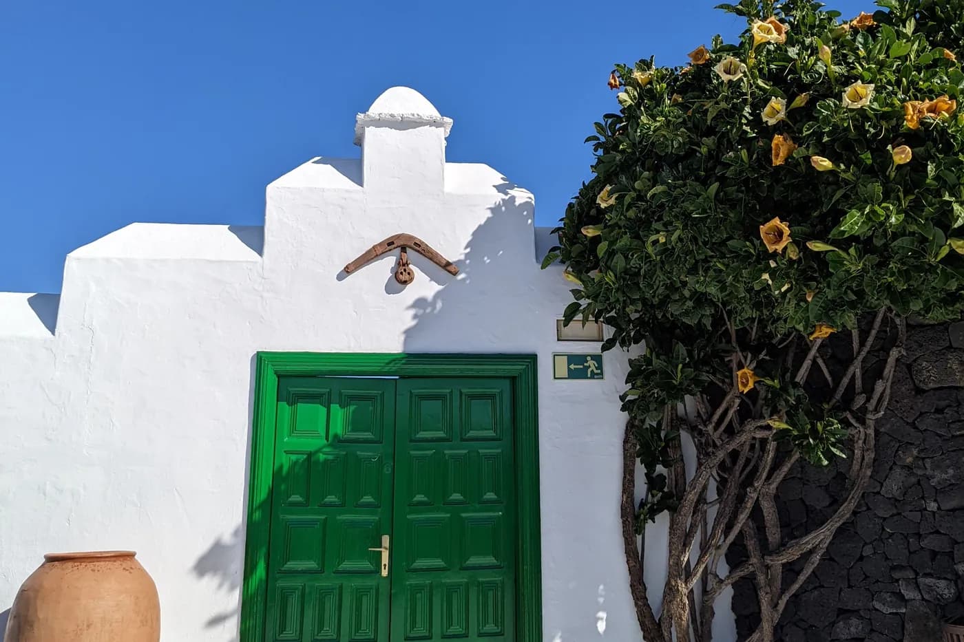 Traditionelle weiße Fassade in Teguise mit grüner Doppeltür und einem Tonkrug