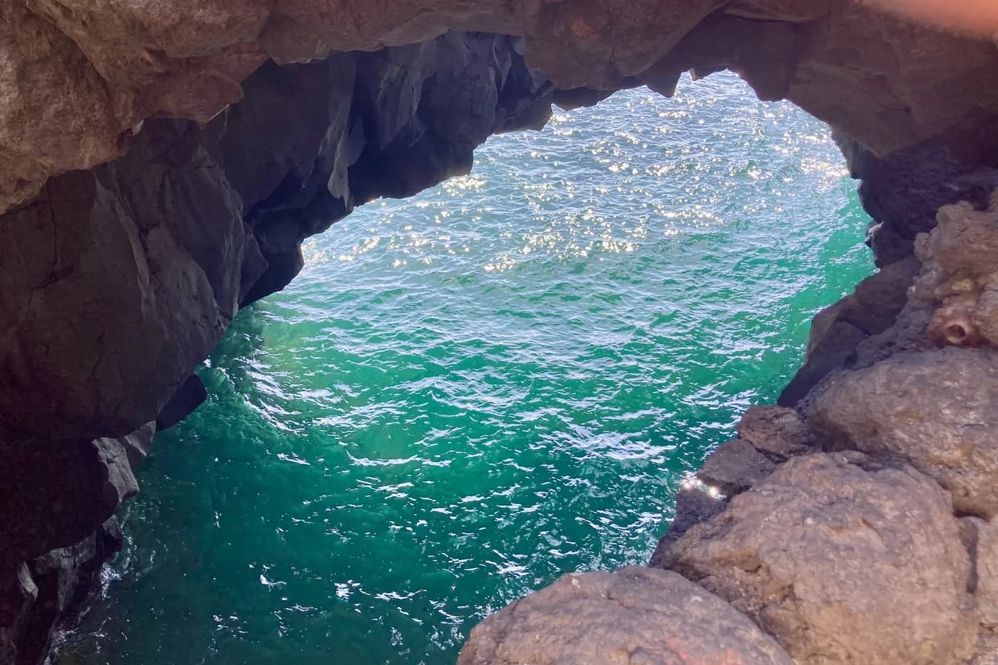 Blick von oben auf eine Meereshöhle mit türkisen Reflexen bei Los Hervideros, Lanzarote