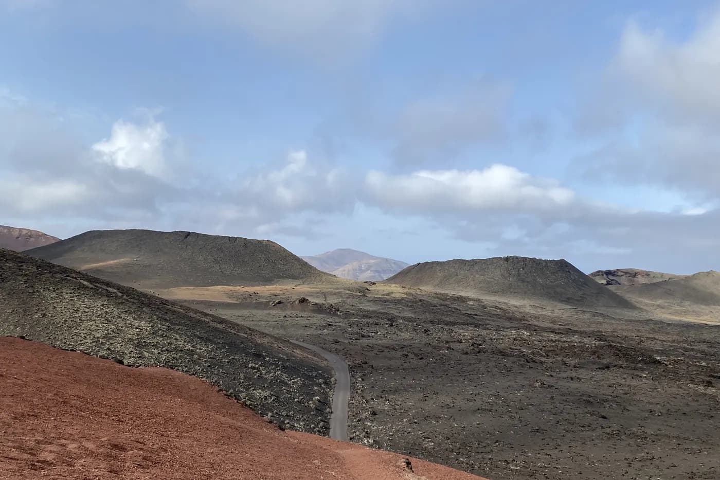Schmale Straße, die sich zwischen den Vulkanen des Nationalparks Timanfaya schlängelt