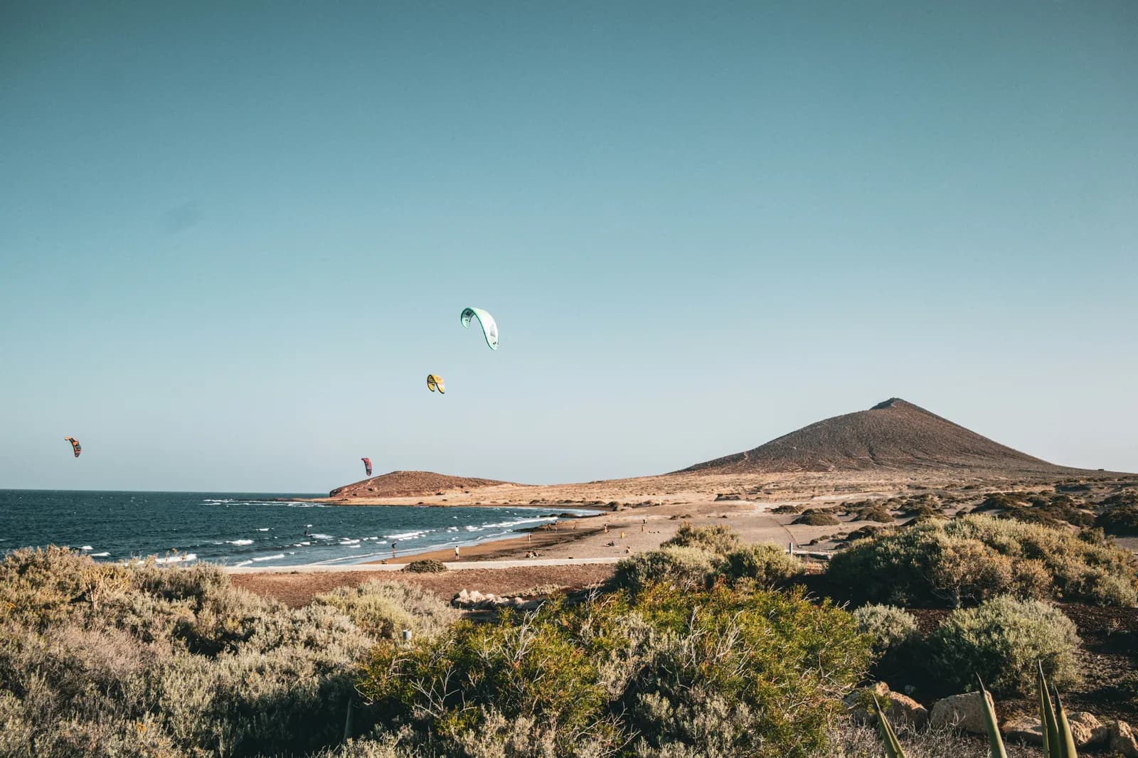 Kitesurfer und bunte Segel am windigen Strand El Médano, Teneriffa